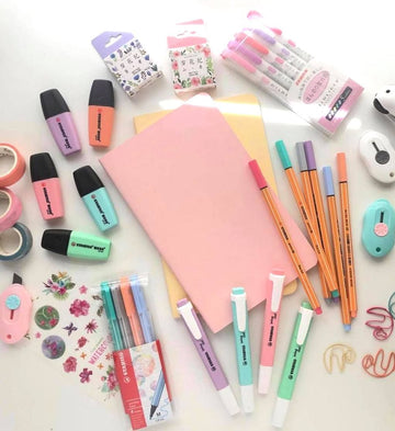 Assorted stationery items including pens, markers, and a notebook on a white background