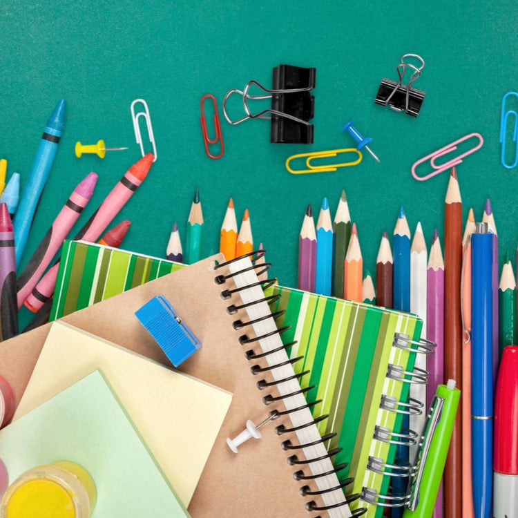 Assorted school supplies including pencils, crayons, and notebooks on a green background